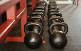 Black kettlebells lined up in a gym, ready for fitness training.